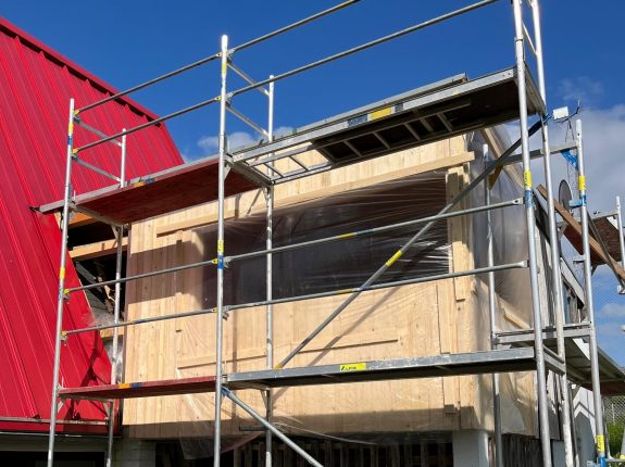 Holzfassade in Lärche mit vertikaler Verschalung und Baugerüst