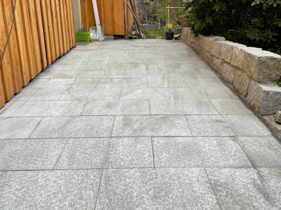 Terrasse mit großformatigem Granitpflaster und Holzfassade