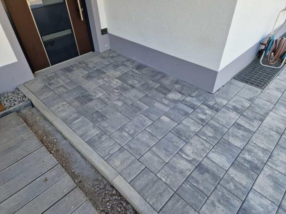 Eingangsbereich mit Podest und schmalem Betonsteinpflaster