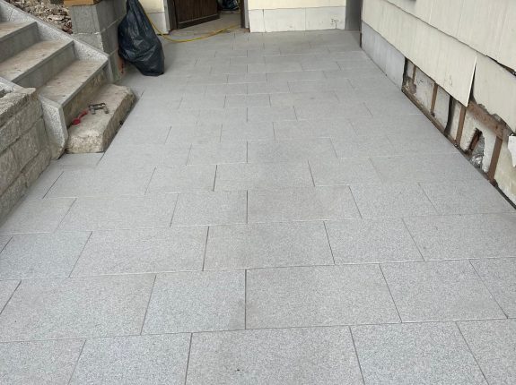 Terrasse mit hellgrauem Natursteinpflaster direkt am Haus