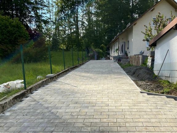 Lange Einfahrt mit geradlinigem Rechteckpflaster in heller Natursteinoptik