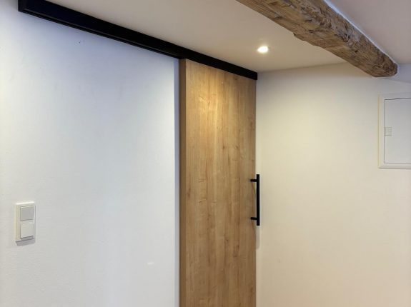 Platzsparende Schiebetür aus Holz – elegant eingebaut mit sichtbarer Laufschiene